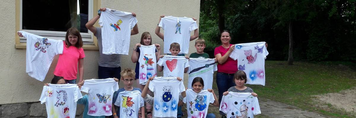 Gruppe von Kinder mit Betreuerin halten selbst bemalte T-Shirts hoch ©Stadt Laatzen