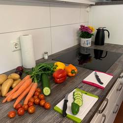 Auf der Küchenzeile liegen Gemüse und Küchenutensilien