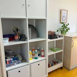 Schrank mit diversen Bastelmaterialien wie Farbe, Pinsel und Stifte