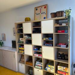 Spieleregalwand mit vielen quadratischen Fächern voller Spiele