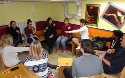 Jugendliche sitzen in einem Kreis und zeigen aufeinander