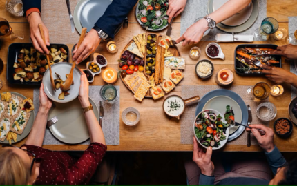 Obenansicht eines gedeckten Tisches mit Leuten, die sich Essen auftun