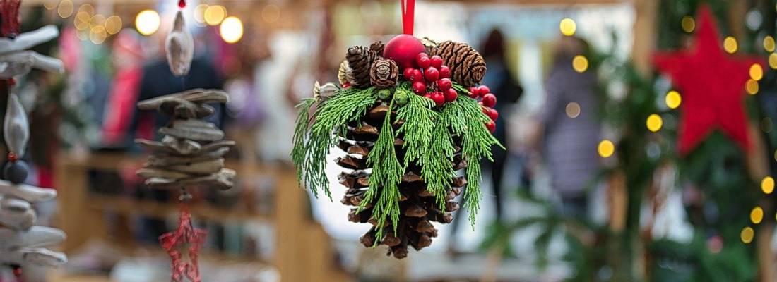 geschmückter Tannenzapfen in Nahaufnahme vor einem Weihnachtsmarktstand