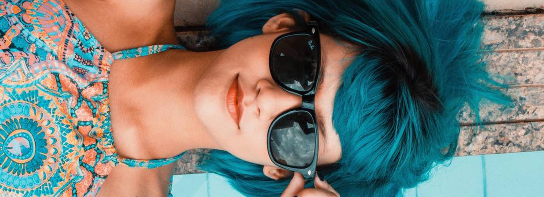 Mädchen mit Sonnenbrille liegt nebem dem Pool
