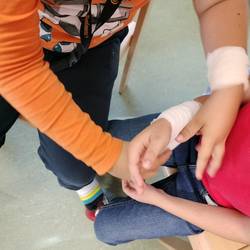 Kind wickelt einen Verband am Unterarm