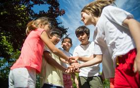 Kinder reichen sich bei schönem Wetter die Hände im Kreis
