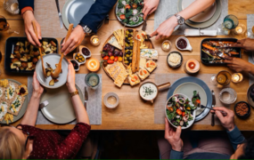 Obenansicht eines gedeckten Tisches mit Leuten, die sich Essen auftun