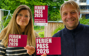 Ein Mann und eine Frau halten die Werbematerialien zum Sommerferienpass in die Kamera.