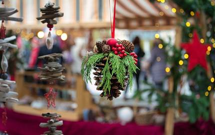 geschmückter Tannenzapfen in Nahaufnahme vor einem Weihnachtsmarktstand