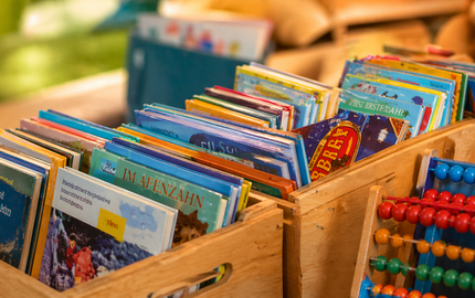 verschiedene Bücherkisten, ein Abakus lehnt davor