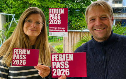 Ein Mann und eine Frau halten die Werbematerialien zum Sommerferienpass in die Kamera.