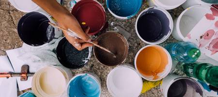 verschieden Farbtöpfe, aus denen die Hand einer Person mit einem Pinsel Farbe entnimmt ©Pixabay