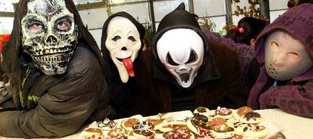 Vier Kinder verkleidet mit Halloweenmasken, im Vordergrund steht ein Tablet mit verzierten Keksen