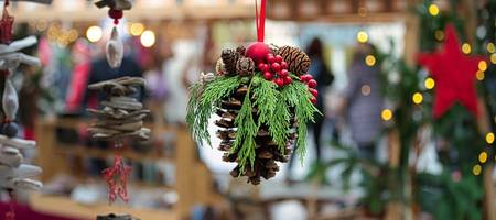 geschmückter Tannenzapfen in Nahaufnahme vor einem Weihnachtsmarktstand