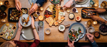Obenansicht eines gedeckten Tisches mit Leuten, die sich Essen auftun