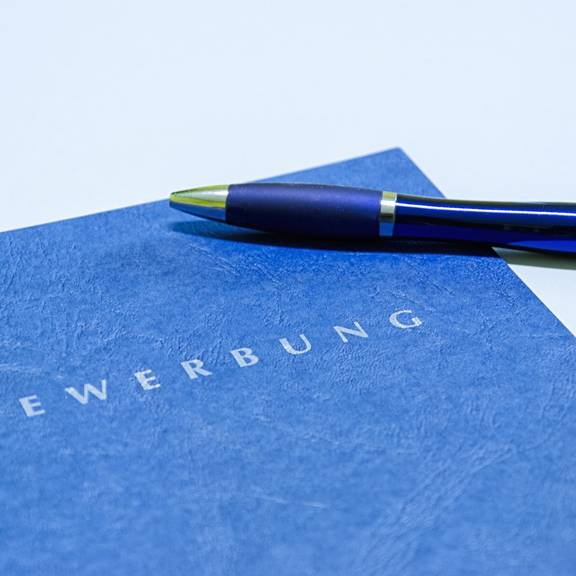 Blaue Bewerbungsmappe mit Stift