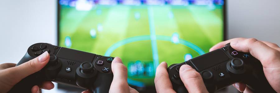Zwei Hände mit Controller beim Fußball Game Spielen